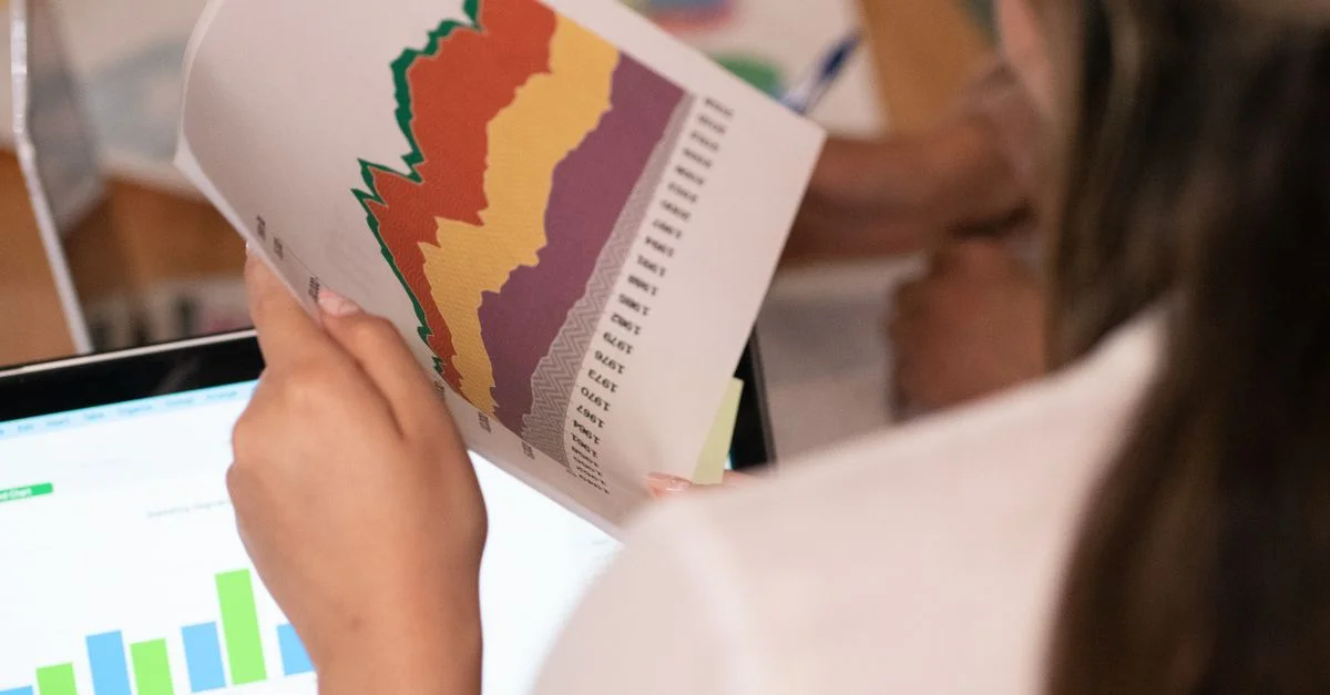 Primer plano de una mujer analizando gráficos y gráficos coloridos en un entorno de oficina.