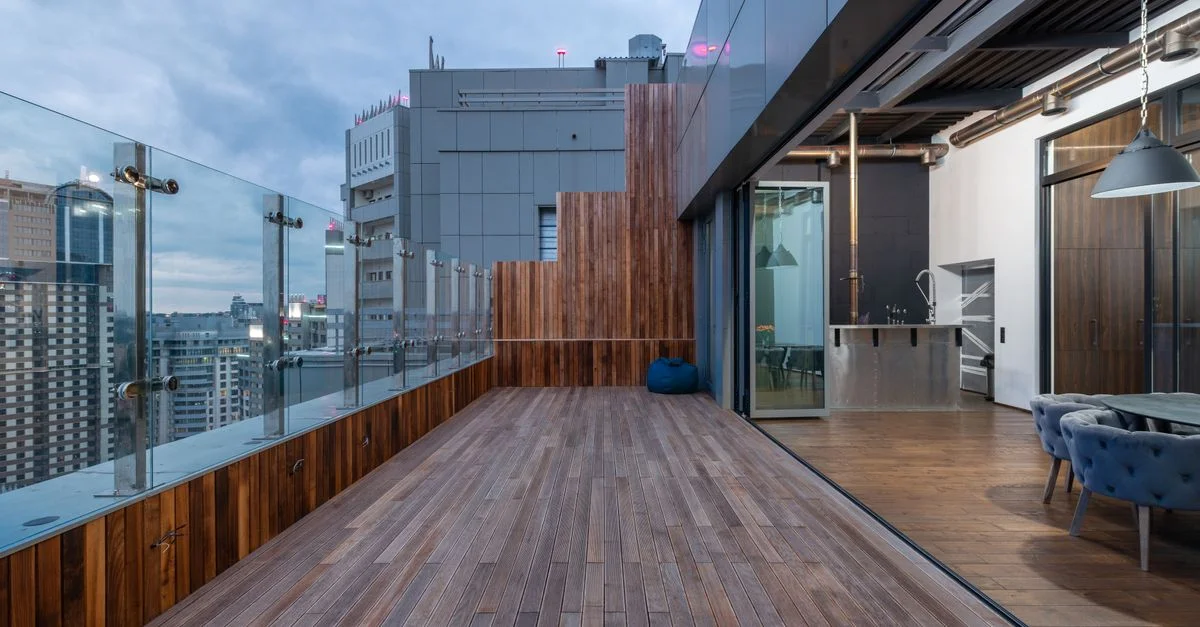 Amplia terraza de madera en edificio alto con horizonte urbano.
