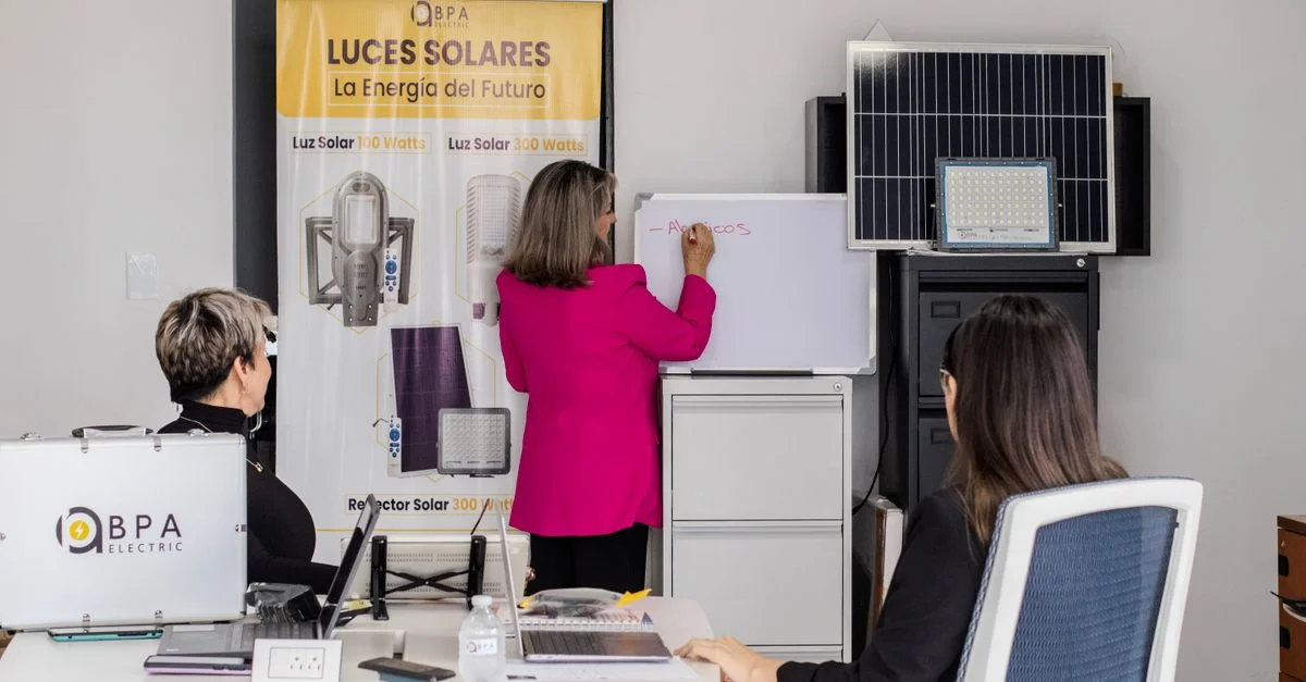 Un equipo comprometido en la lluvia de ideas sobre soluciones de energía solar con paneles y una pizarra en una oficina.