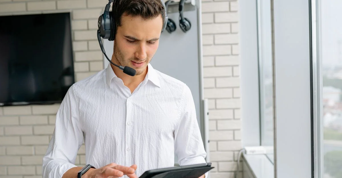 Un hombre que lleva auriculares y usa una tableta en un entorno de oficina moderna.