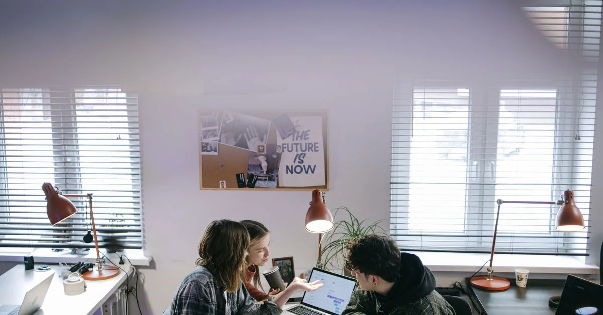 Un grupo de personas discutiendo ideas alrededor de portátiles en un espacio de oficina moderno y luminoso.