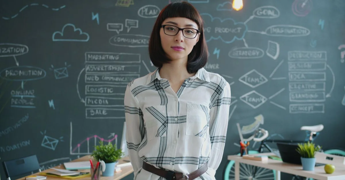 Joven empresaria en una oficina informal con fondo de pizarra y decoración moderna.