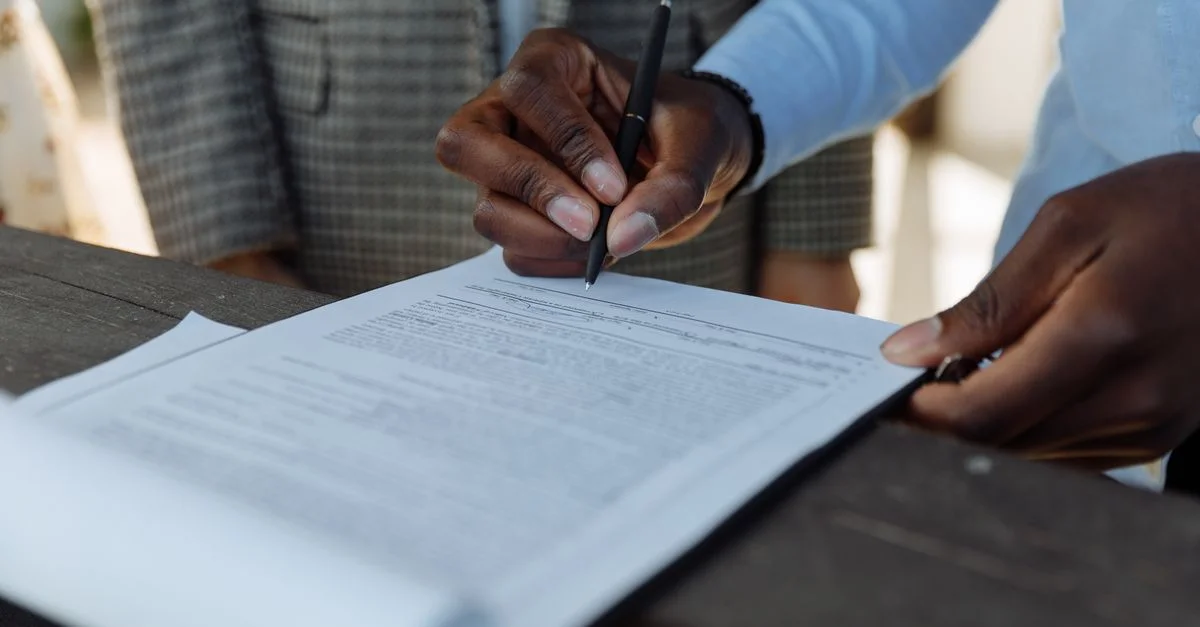 Primer plano de profesionales de negocios firmando un documento con un bolígrafo en interiores.