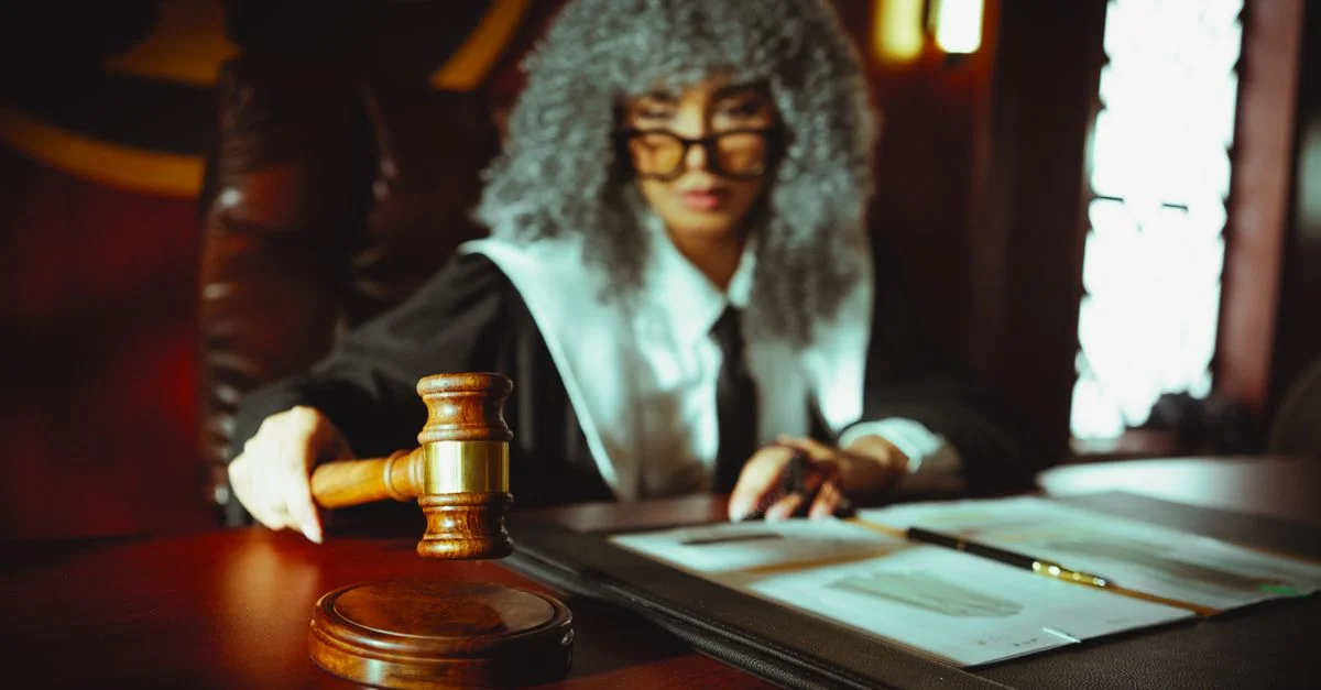 Un juez en una sala judicial sosteniendo un martillo, concentrado en documentos legales.