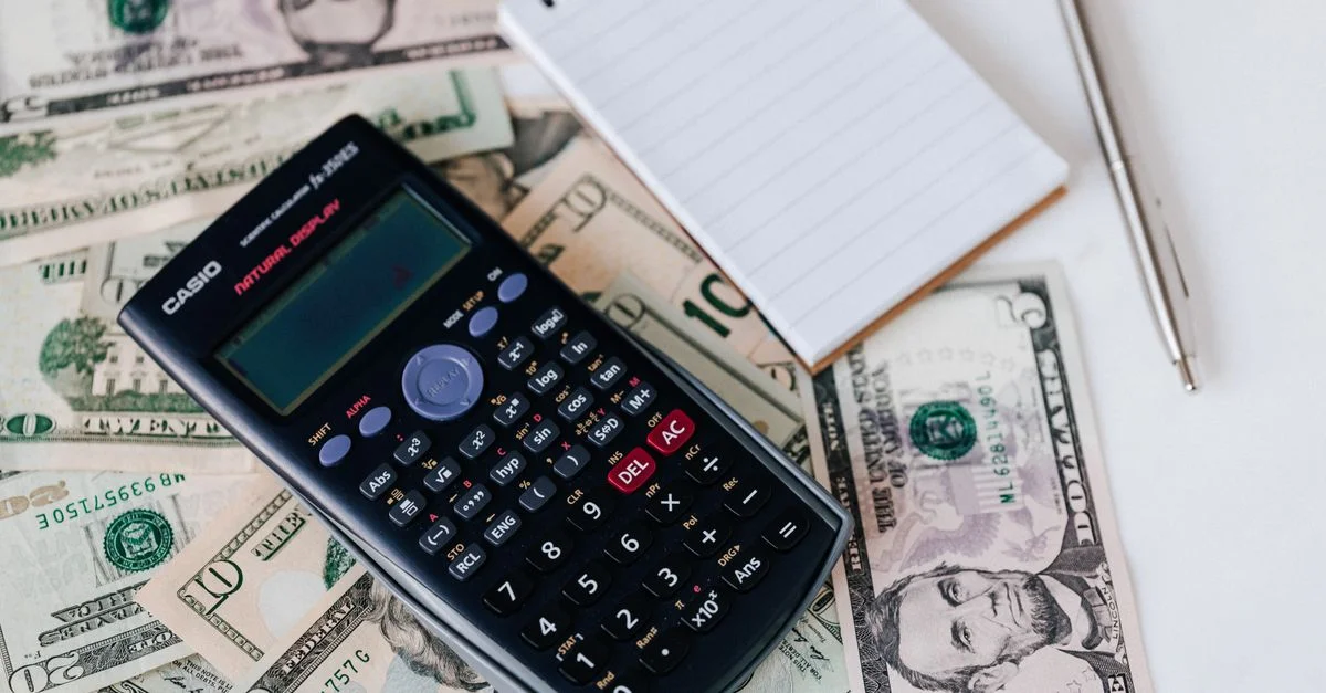 Calculadora, dinero y cuaderno en la mesa para planificación financiera.