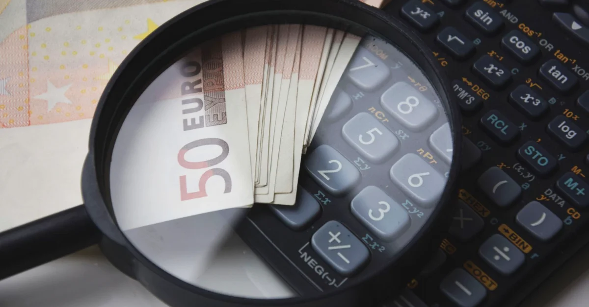 Billetes de euro bajo una lupa con calculadora, simbolizando finanzas y análisis.