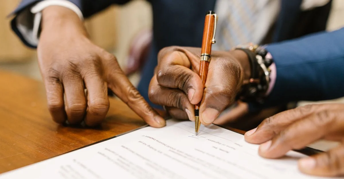 Primer plano de profesionales de negocios firmando un contrato legal en un entorno de oficina.