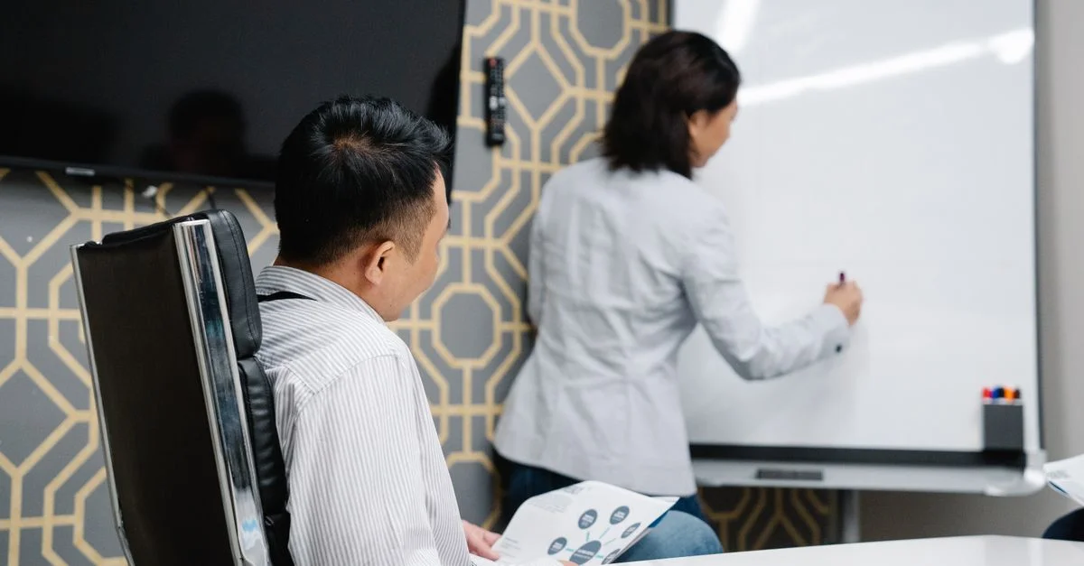 Profesionales de negocios participando en una reunión colaborativa utilizando una pizarra para el brainstorming.